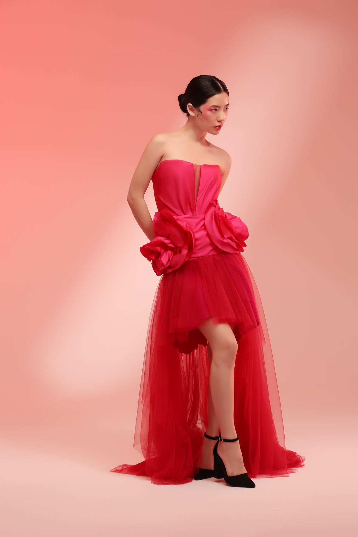 Pink dress in deep v-neck cut with petals draping on hips with micro-pleated mullet skirt